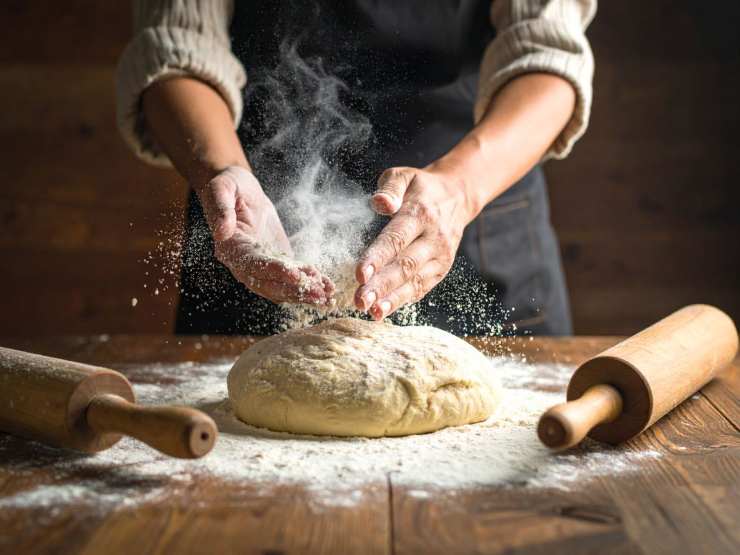 uomo lavora impasto con farina