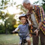 nonno con nipote in con casco in bicicletta