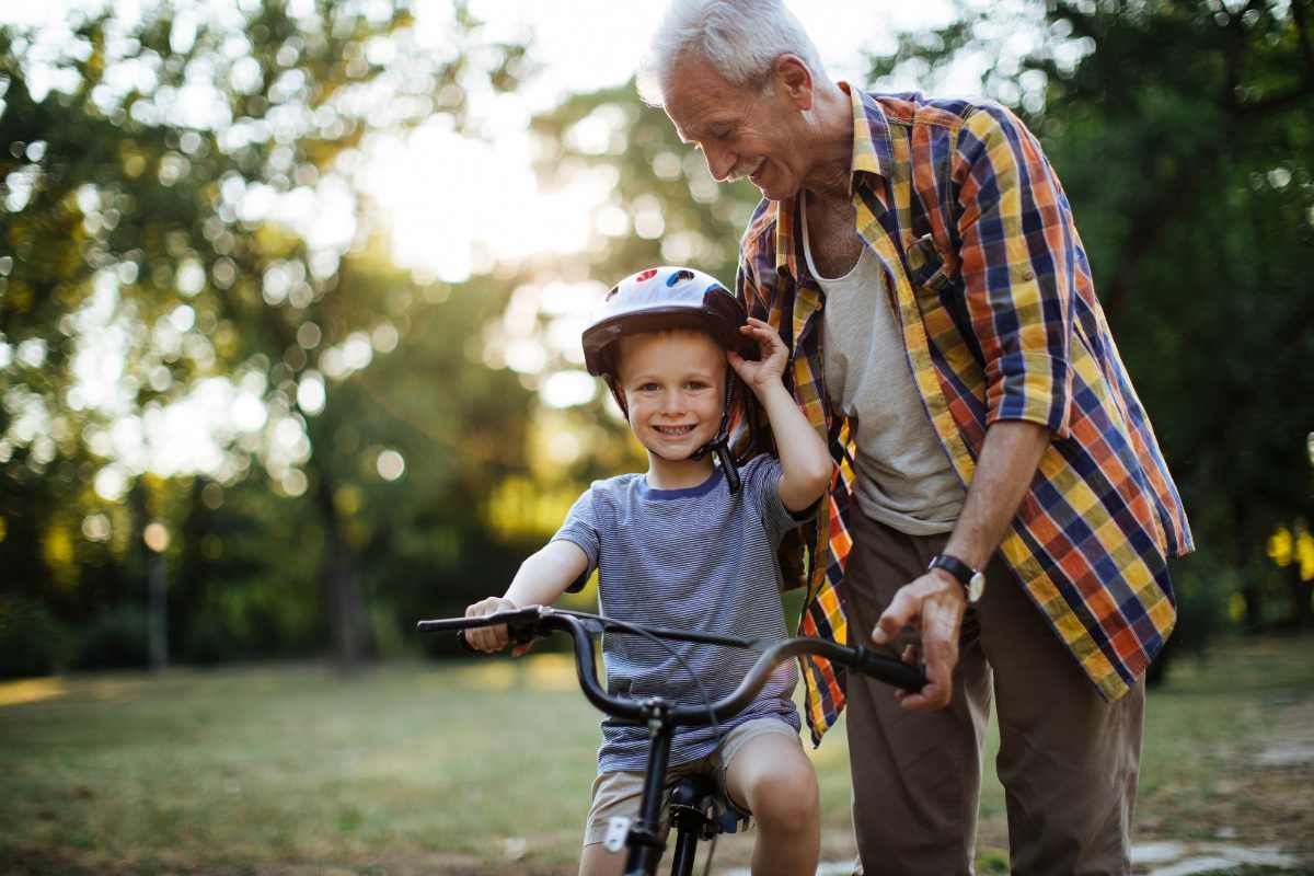 nonno con nipote in con casco in bicicletta